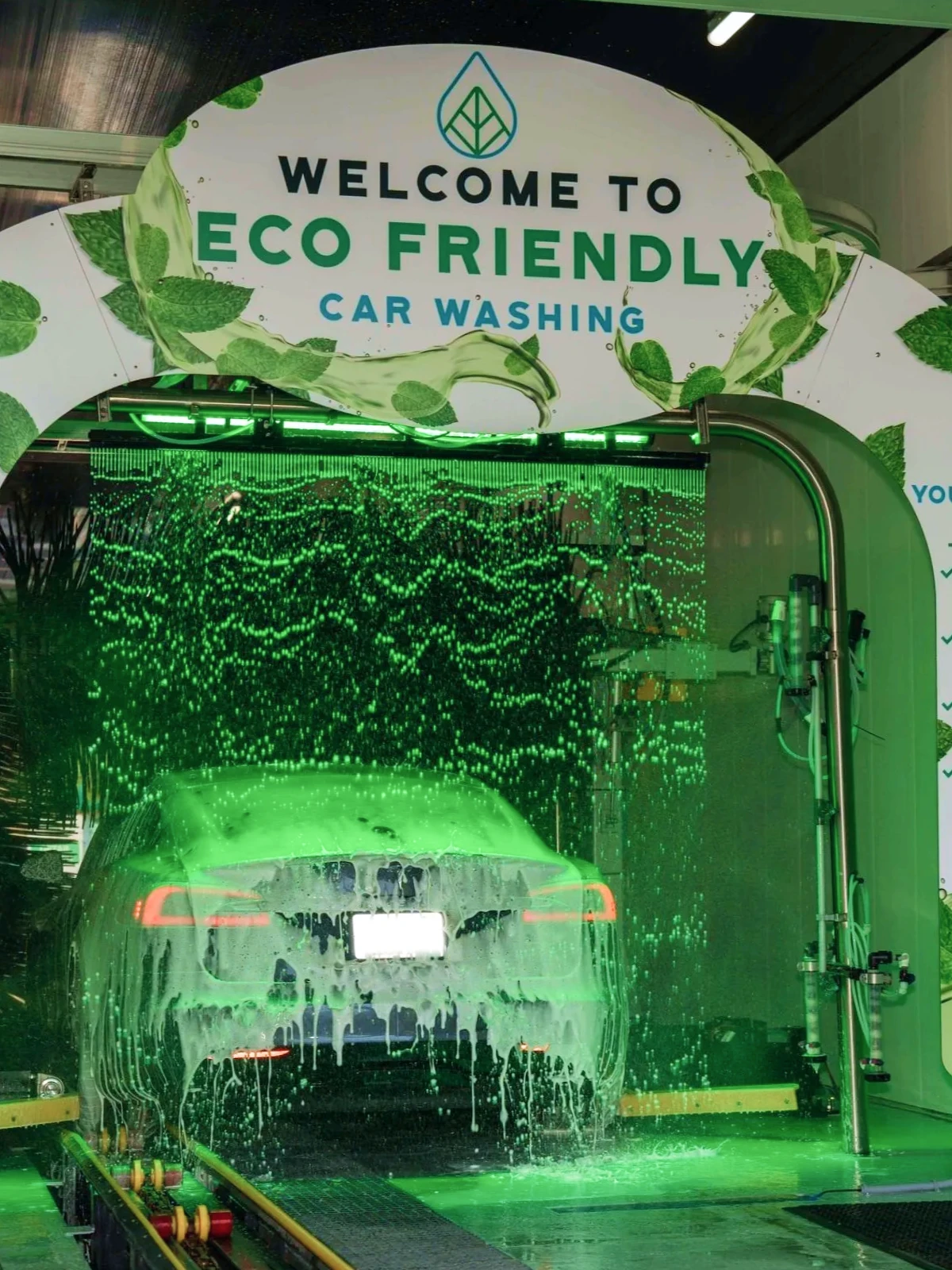 Close-up of a soapy car passing through the green-lit wash tunnel