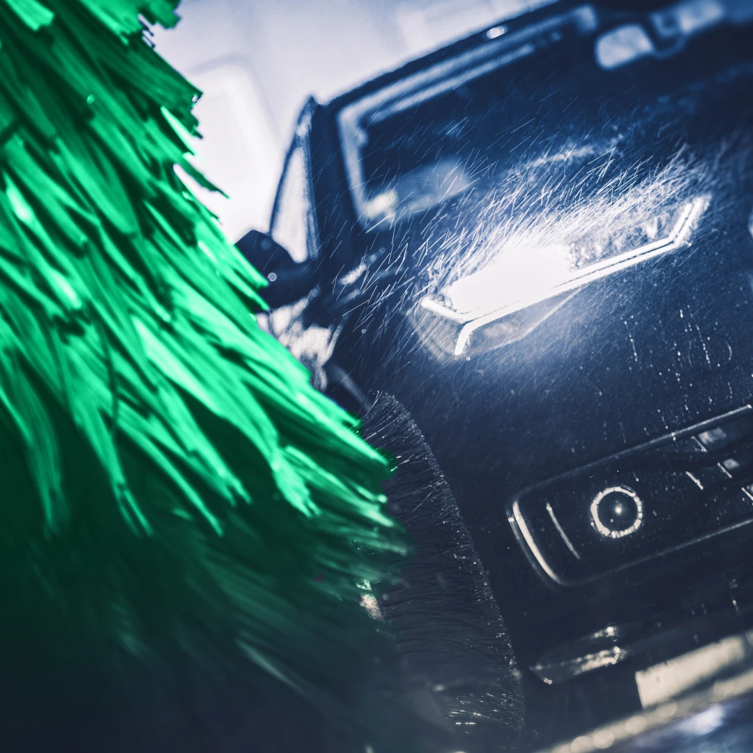 Green foam wash brush cleaning the front of a car inside the Mint Eco wash tunnel