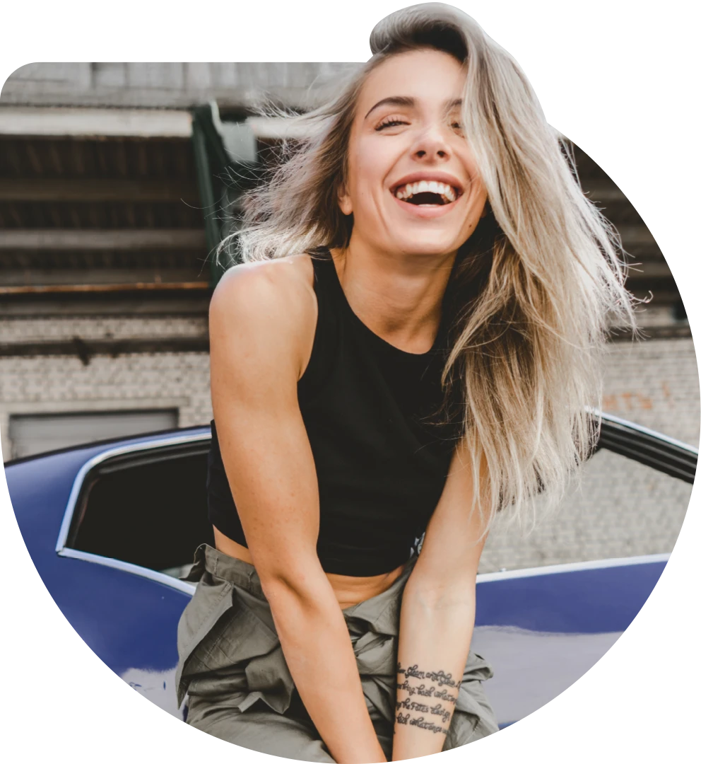 Woman laughing while sitting on a car