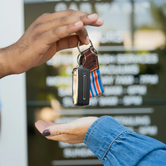 Handing car keys to a customer outside a Mint Eco location