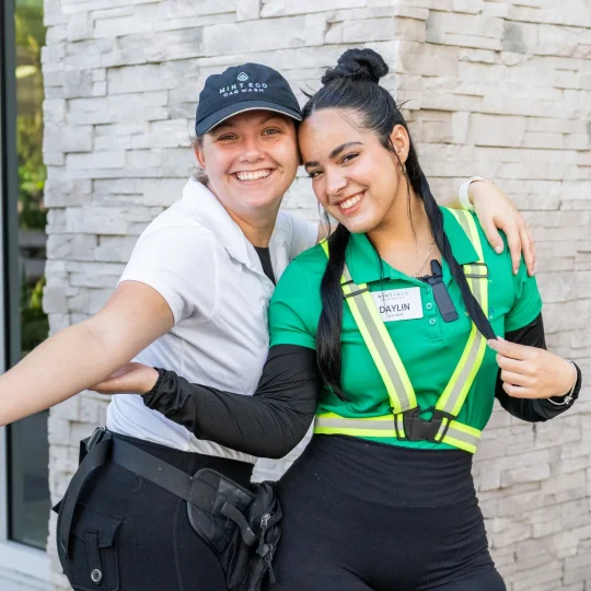 Two Mint Eco employees hugging and smiling