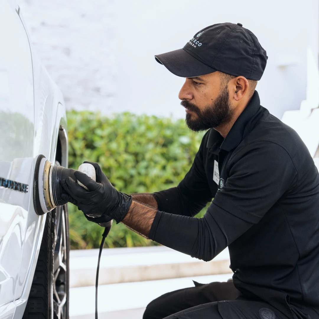 Detail technician buffing a car wheel with a polisher