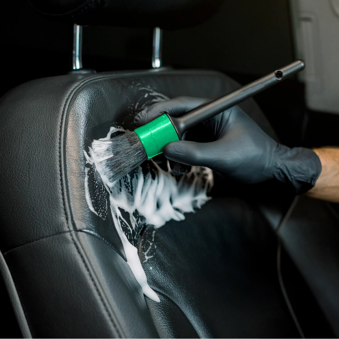 Detailing brush cleaning foam into a car's leather seat