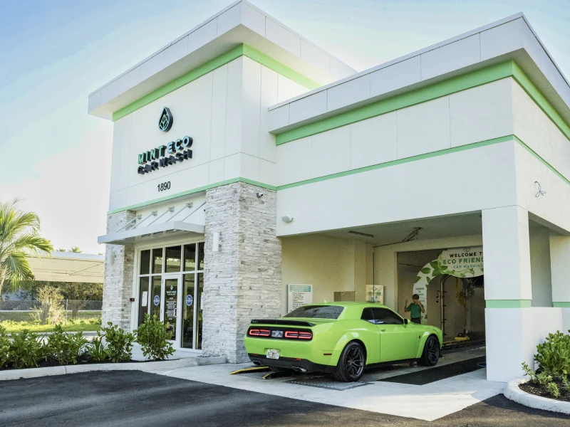 Mint Eco Car Wash Palm Beach Lakes location exterior with a green Dodge Challenger at the entrance