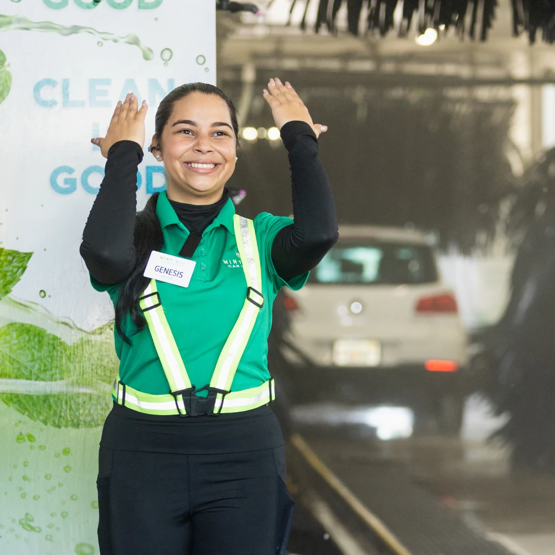 Mint Eco employee waving as a car passes through the wash tunnel