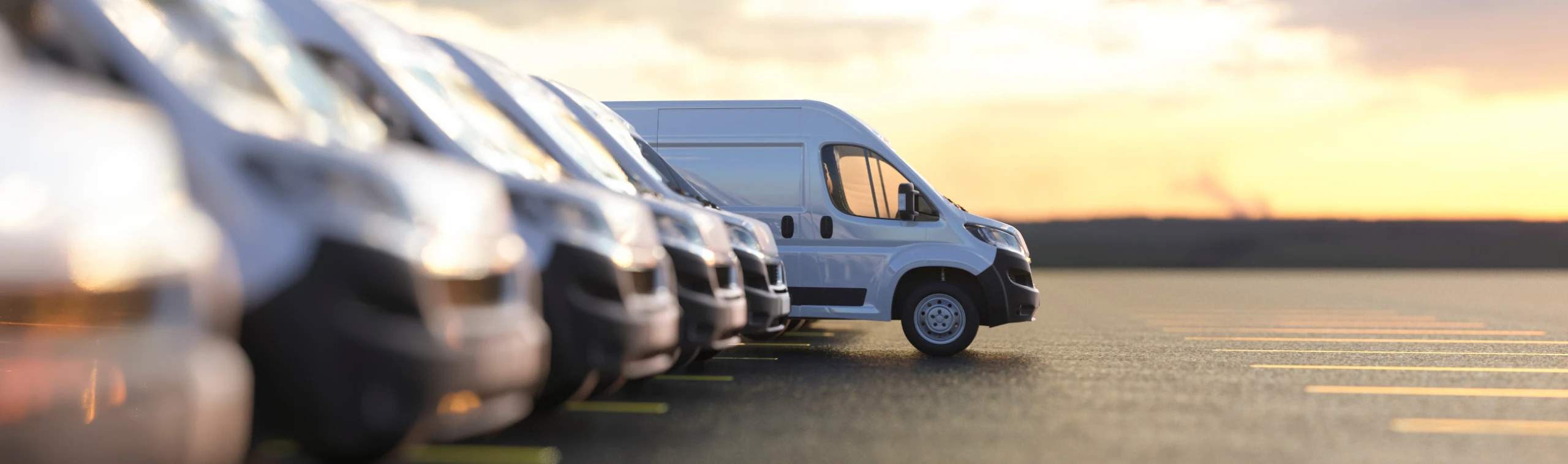 Fleet of white delivery vans lined up at sunset
