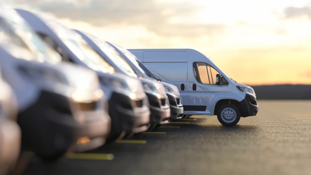 Fleet of white delivery vans lined up at sunset