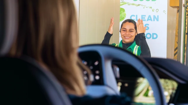Mint Eco attendant waving as a car exits the wash tunnel