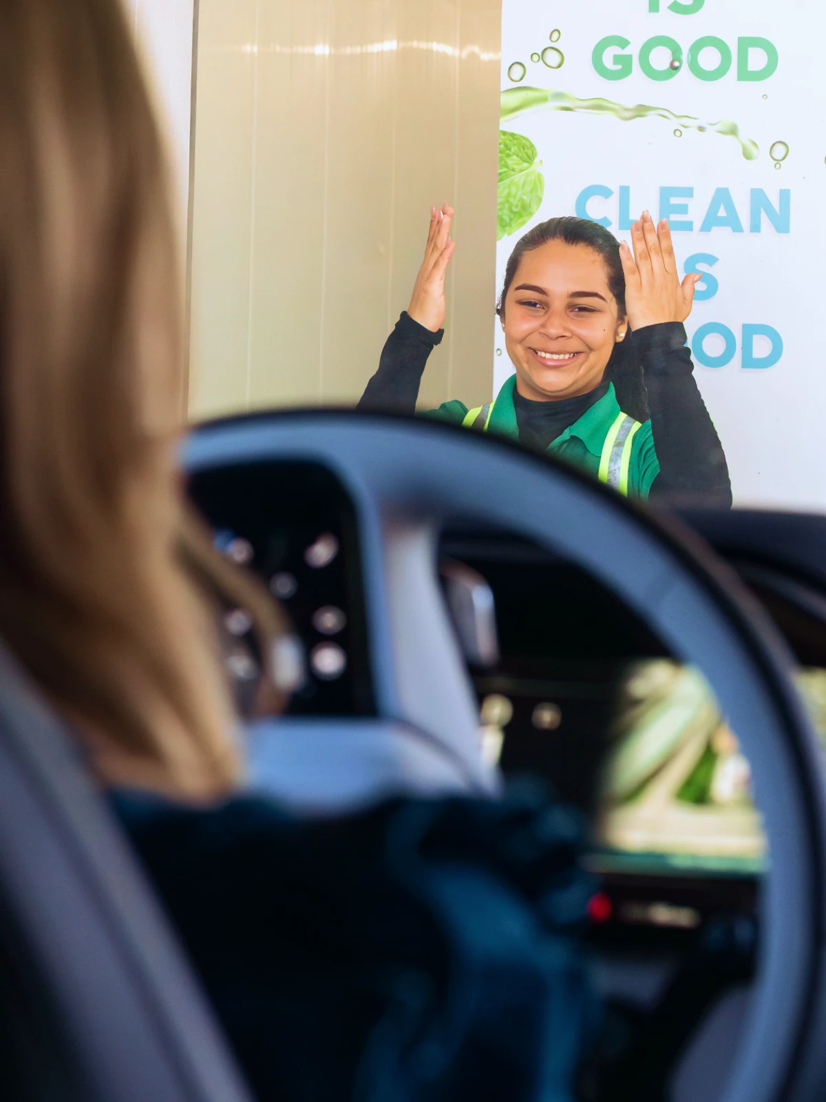 Mint Eco attendant waving as a car exits the wash tunnel
